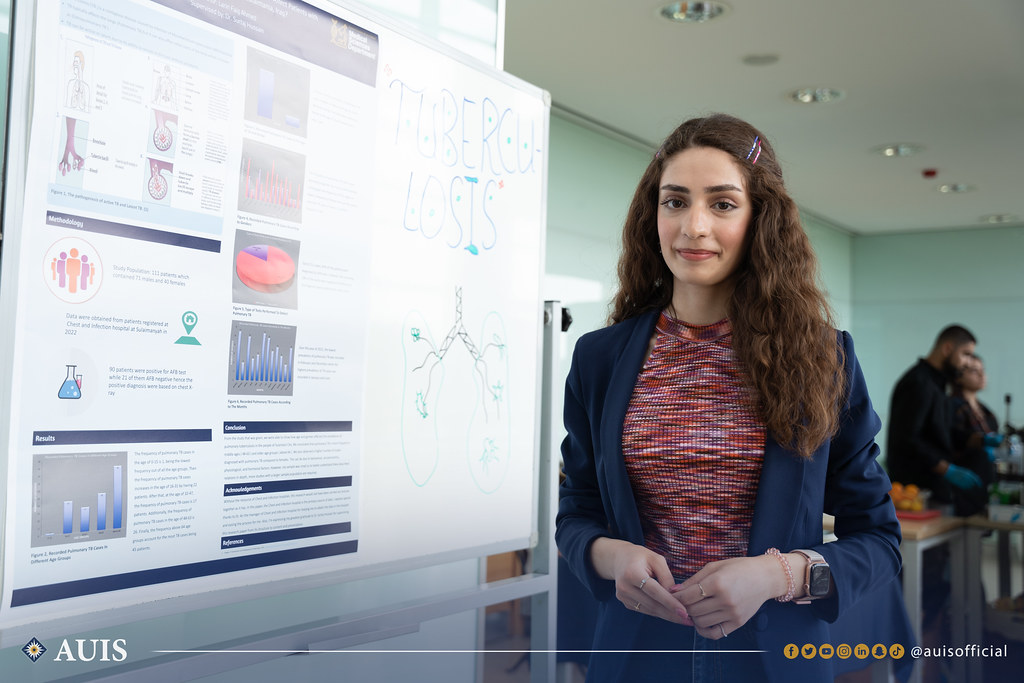 An MLS student poses next to her capstone project poster.
